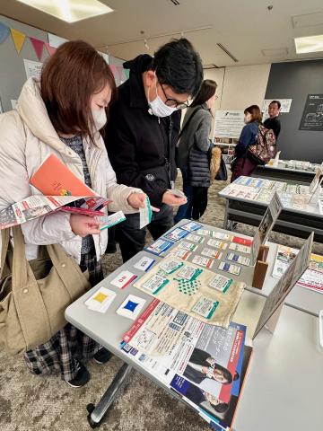 京都SDGsゲームショウの展示ブースにて、複数の来場者が「クロスロード・ダイバーシティゲーム」のカードやパンフレットを手に取り確認しています。DEIコンサルティングやダイバーシティ研修における実践的なツールとして、参加者の深い関心と理解を促しています。